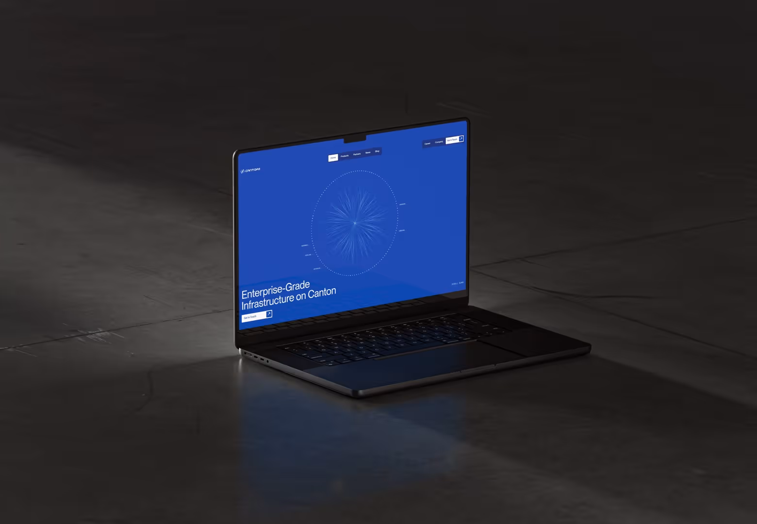 Open laptop on dark floor showing a blue screen with text about enterprise-grade infrastructure on Canton.