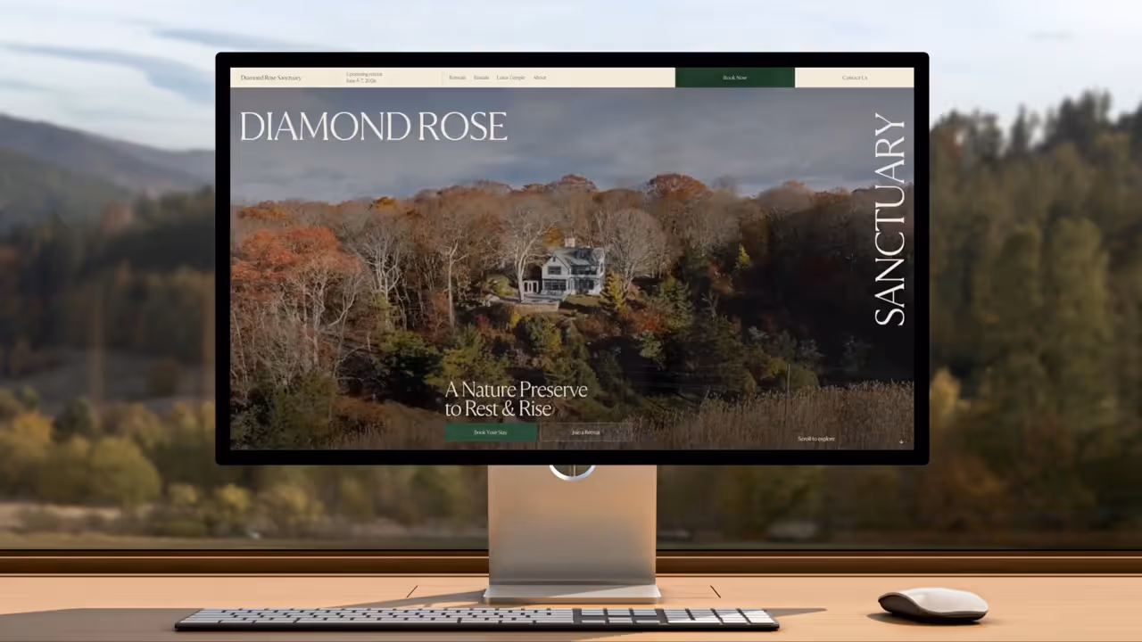 Computer screen on desk showing Diamond Rose Sanctuary website with autumn forest and house.