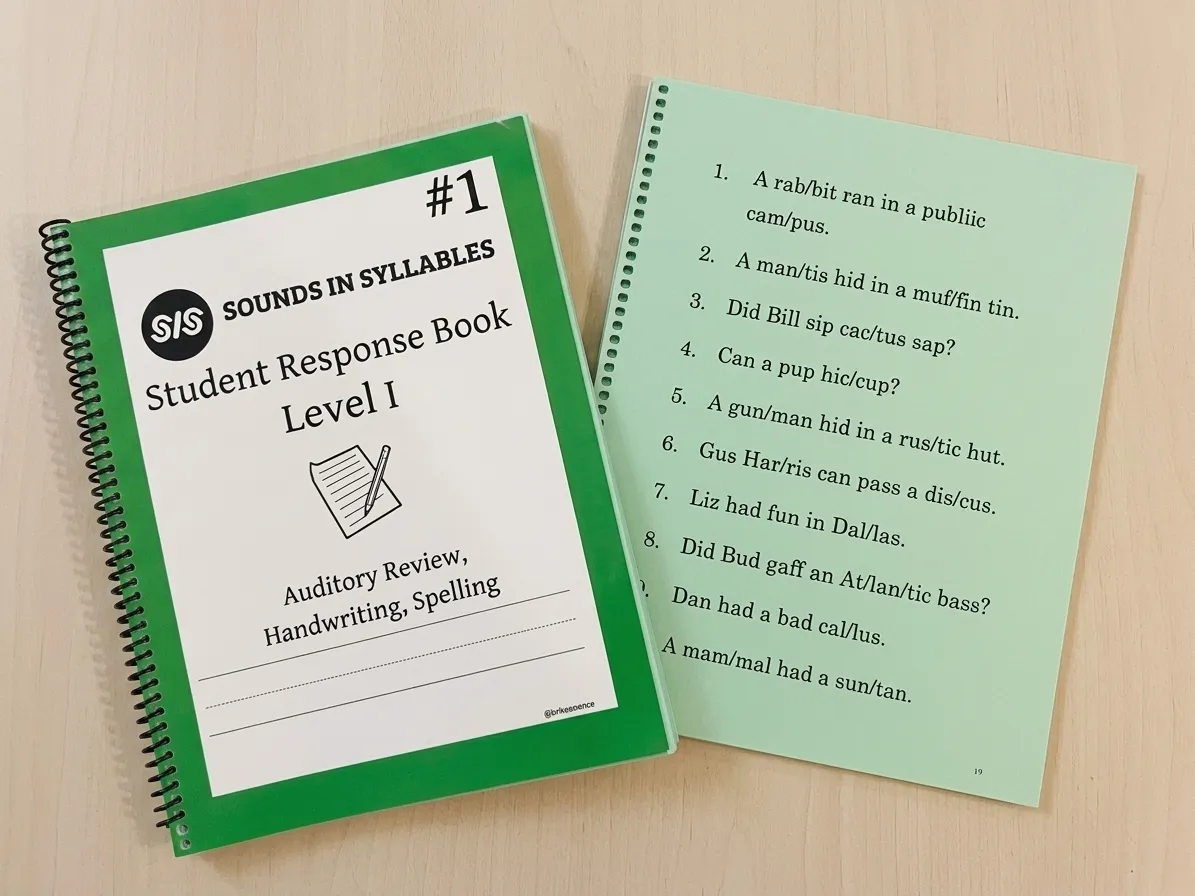 A Sounds in Syllables Student Response Book beside a sheet of syllable-divided practice sentences.
