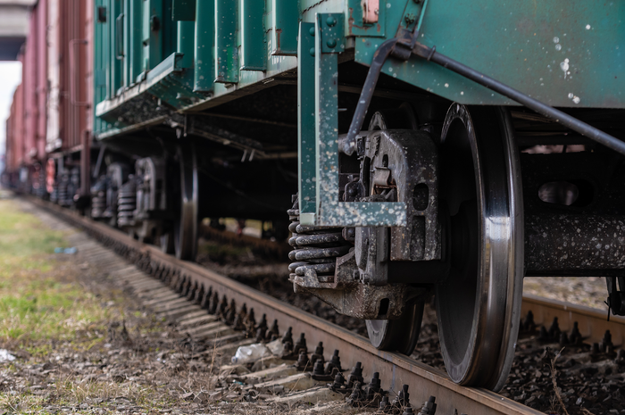 Close-up of the steel wheels and undercarriage of a freight rail car on the tracks