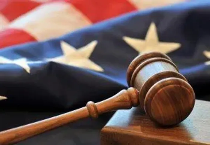 A wooden judge's gavel resting in front of a folded American flag