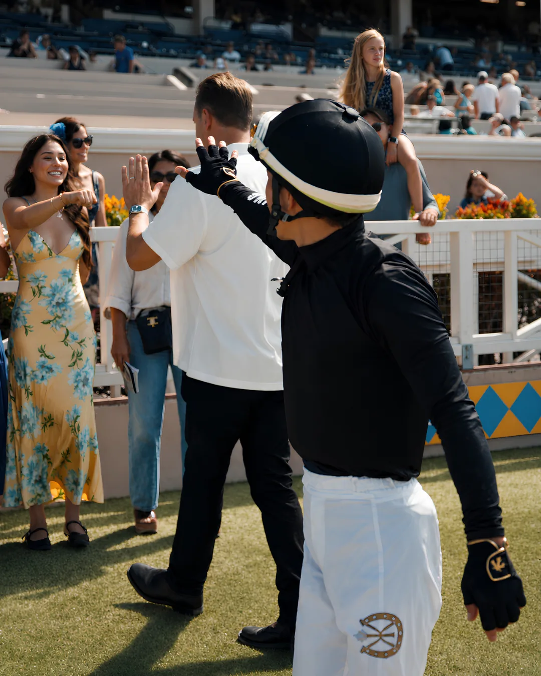 A jockey high-fiving Run Fast Racing guests after the race at Del Mar