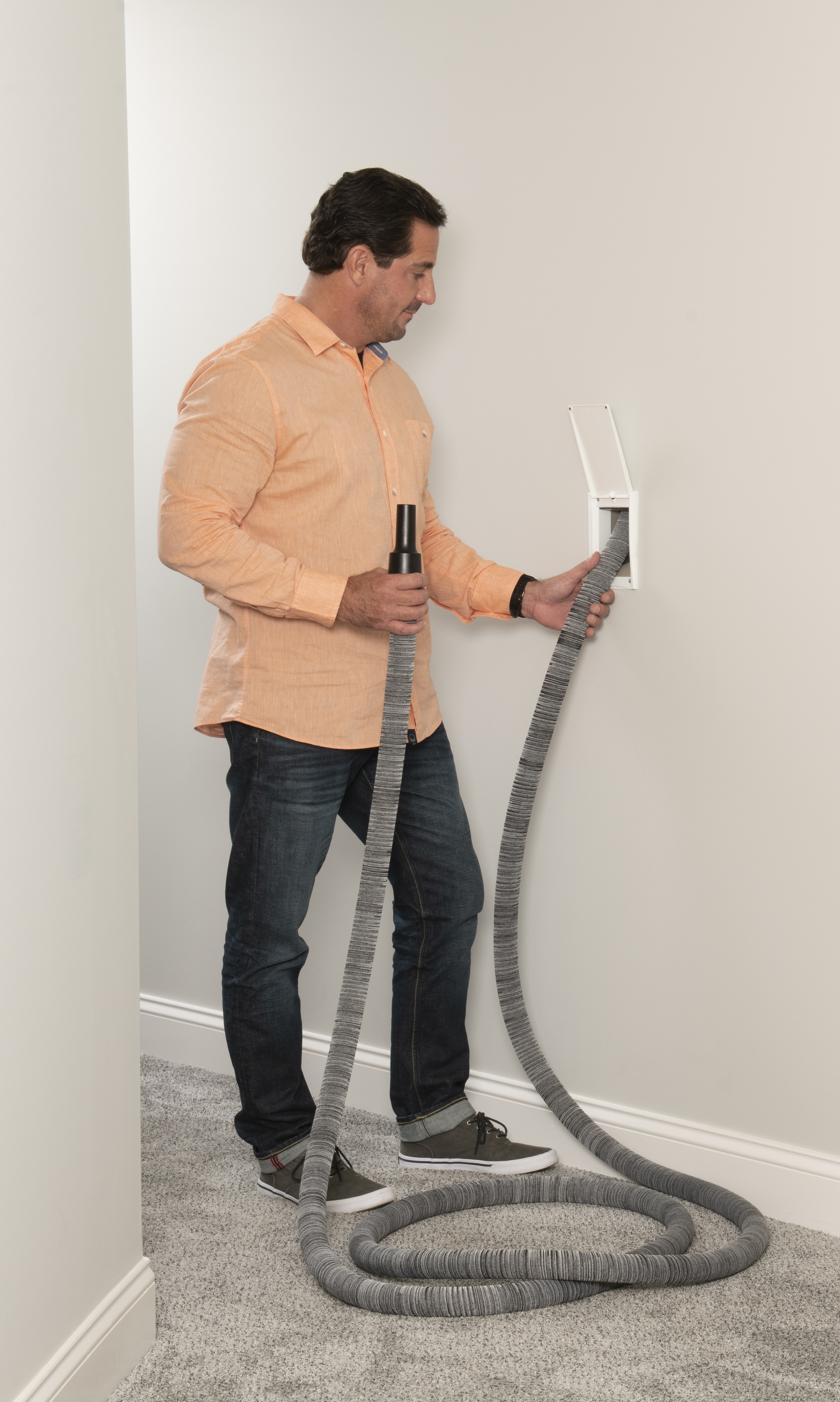 Homeowner using a Coltrin retractable central vacuum hose pulled from a wall valve