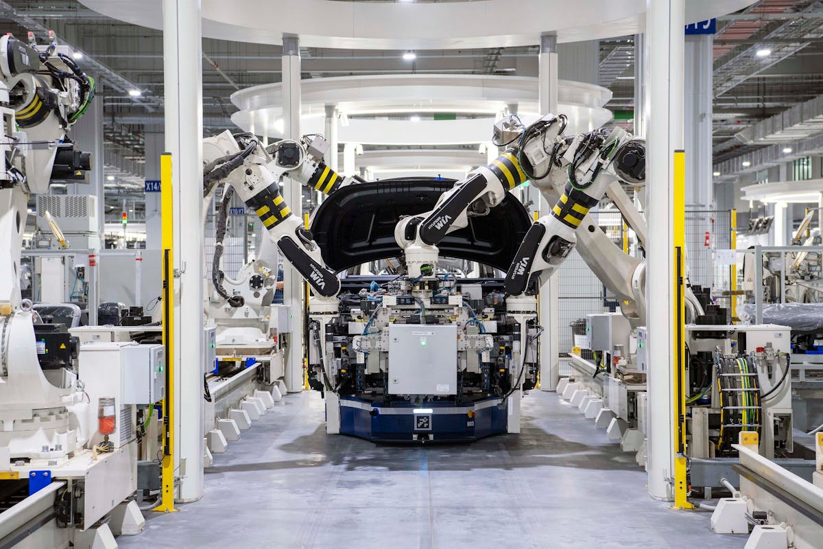 Automated robotic arms assembling a vehicle in a modern automotive manufacturing plant.
