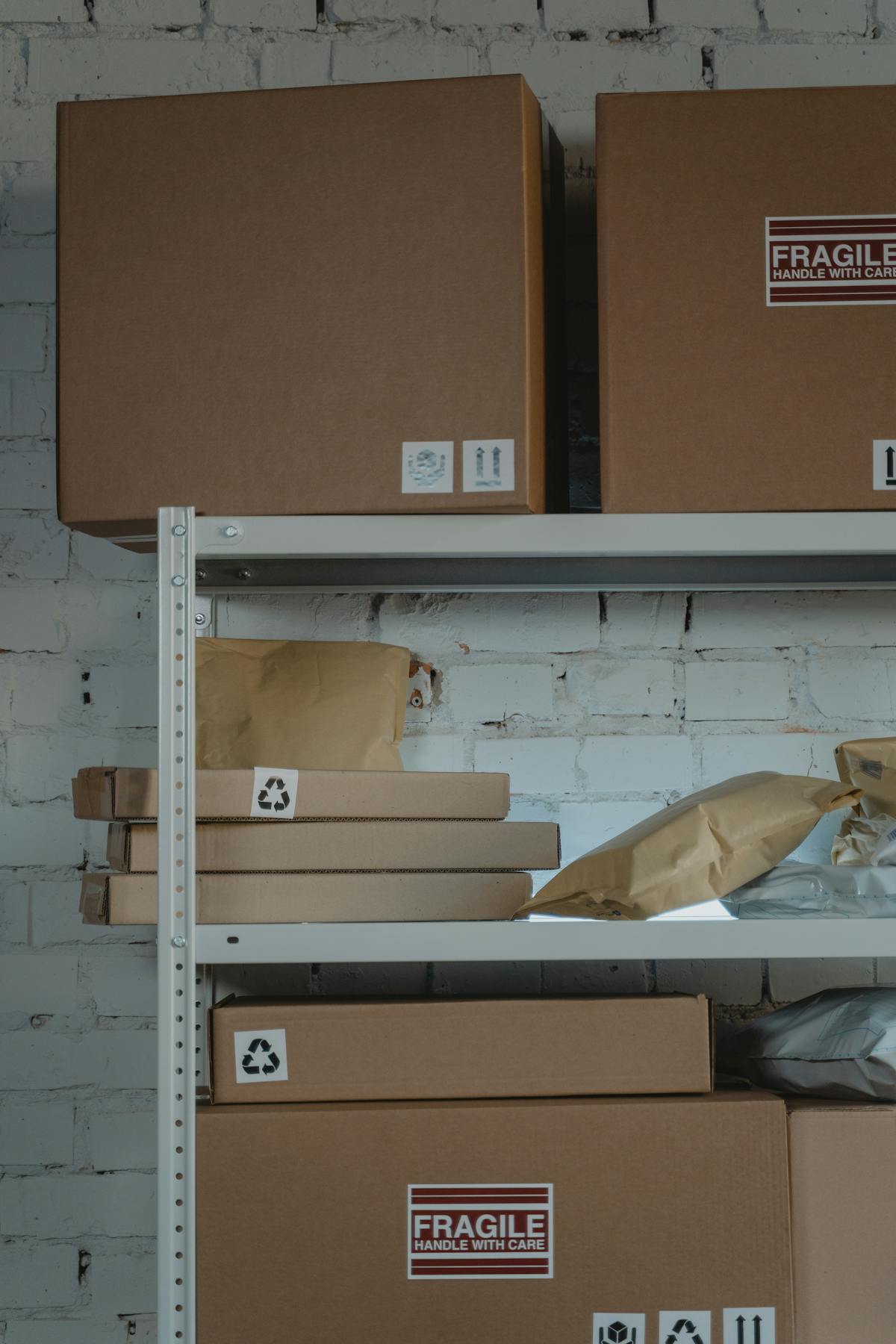 Shelves with cardboard boxes and padded envelopes, some labeled fragile or with recycling symbols.