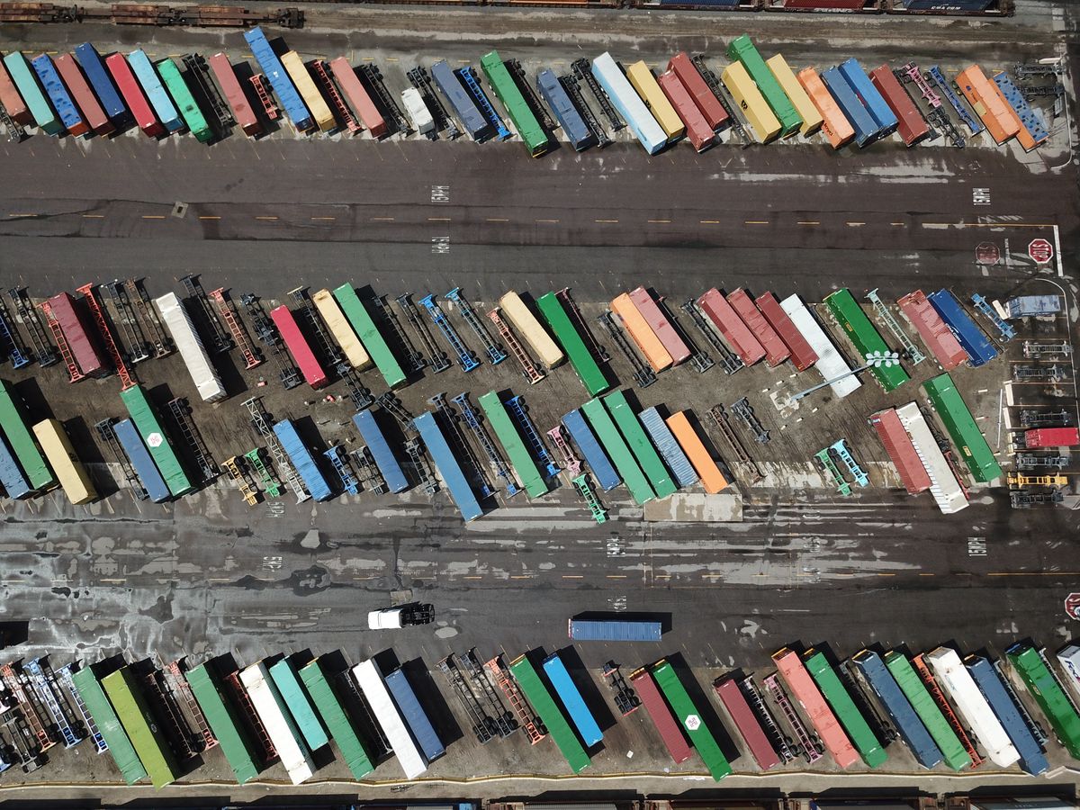 Aerial view of a shipping yard with rows of colorful parked trailers on asphalt lots.