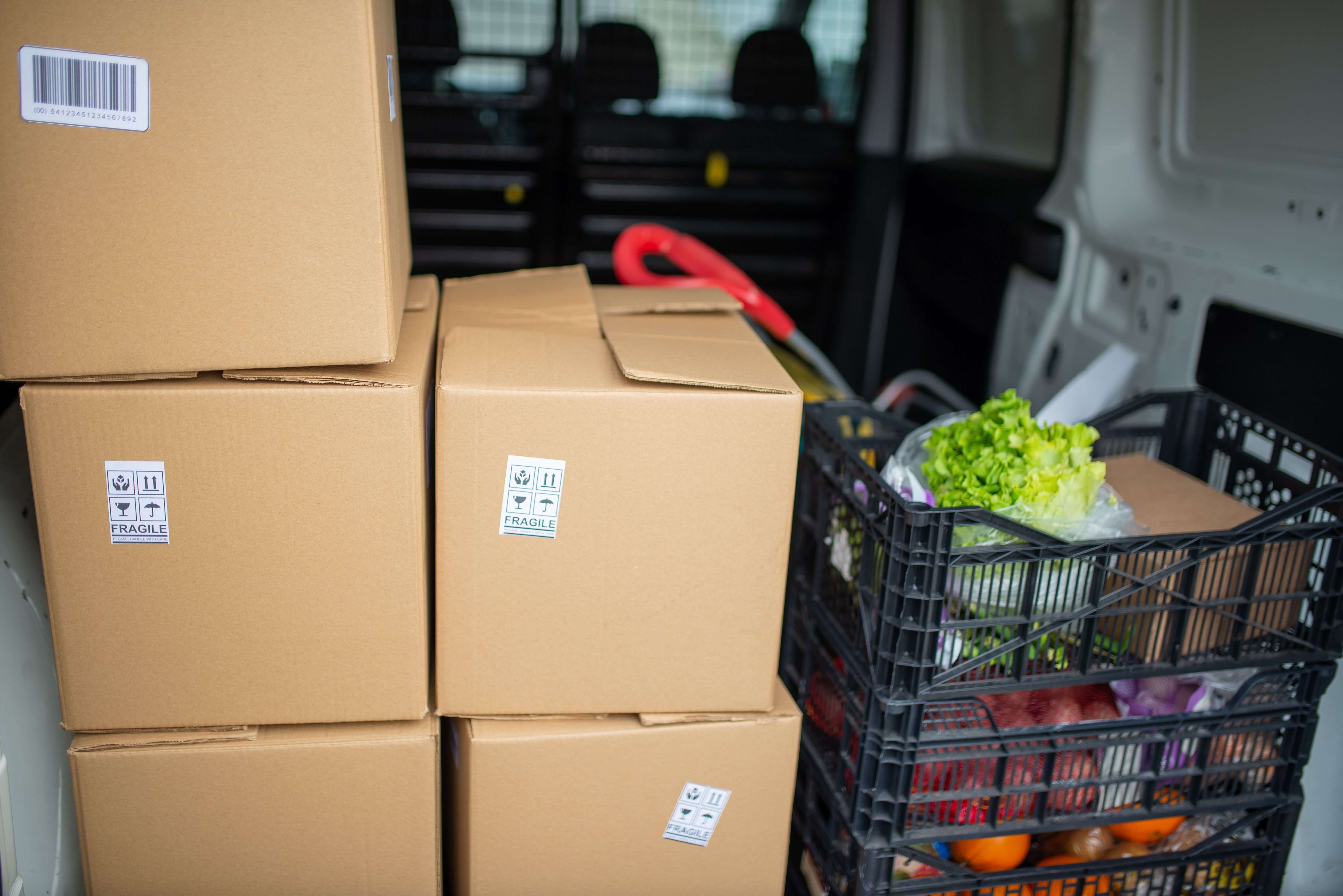 Cardboard shipping boxes stacked with a basket of fresh produce representing food and beverage packaging logistics