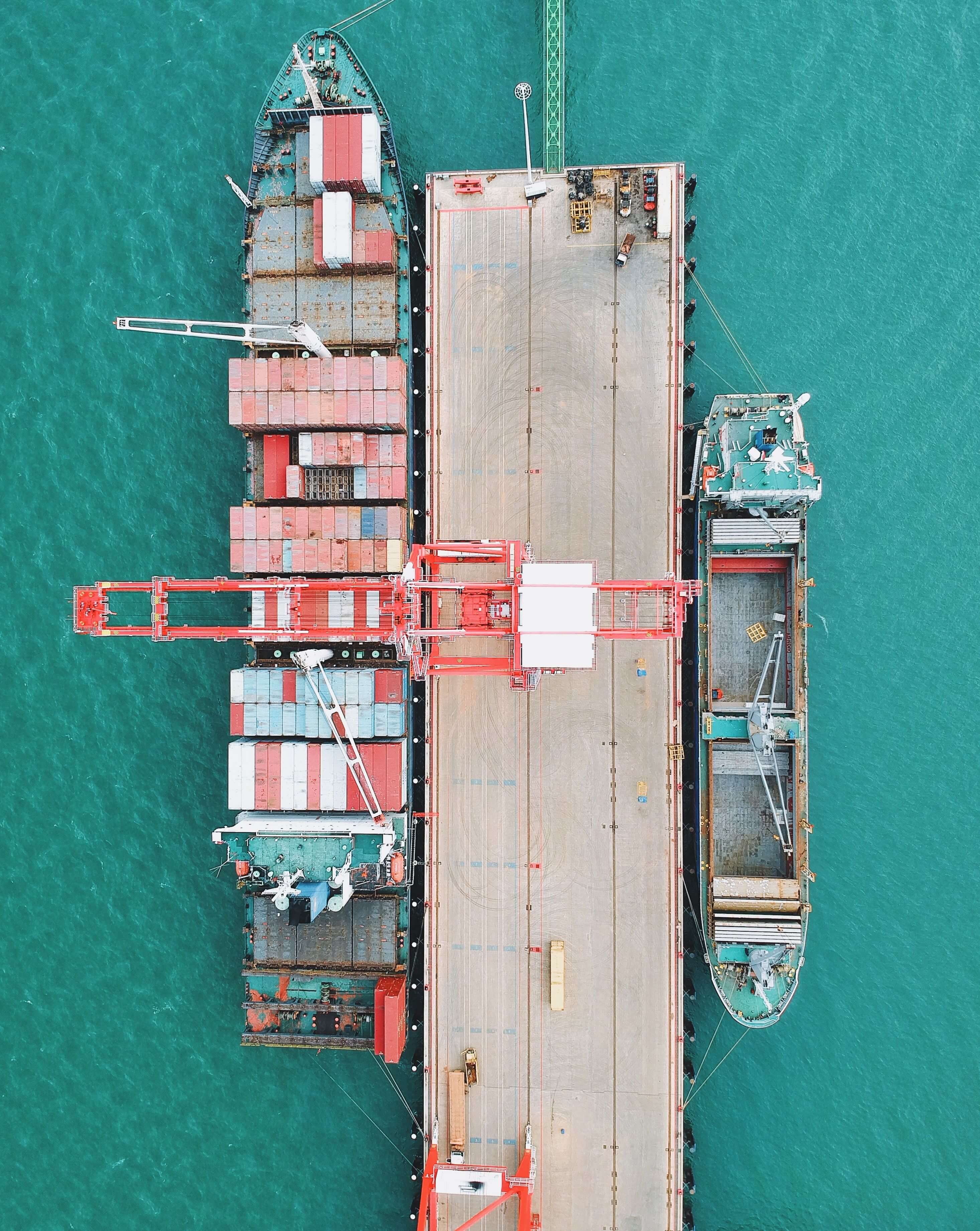 Aerial view of a cargo ship docked at a green shipping terminal