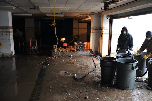 Dimly lit basement with scattered tools and equipment on concrete floor.