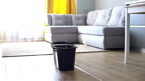 Water droplets leaking in bucket from ceiling