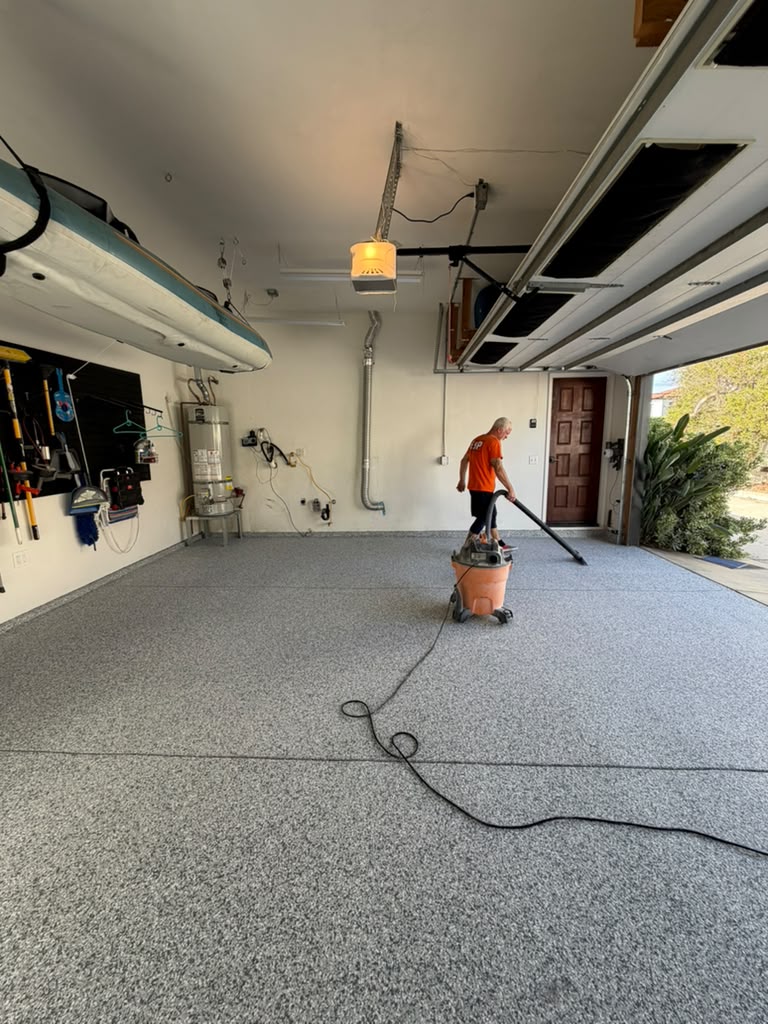 Crew member vacuuming loose Gravel flakes off the base coat before the seal coat goes on