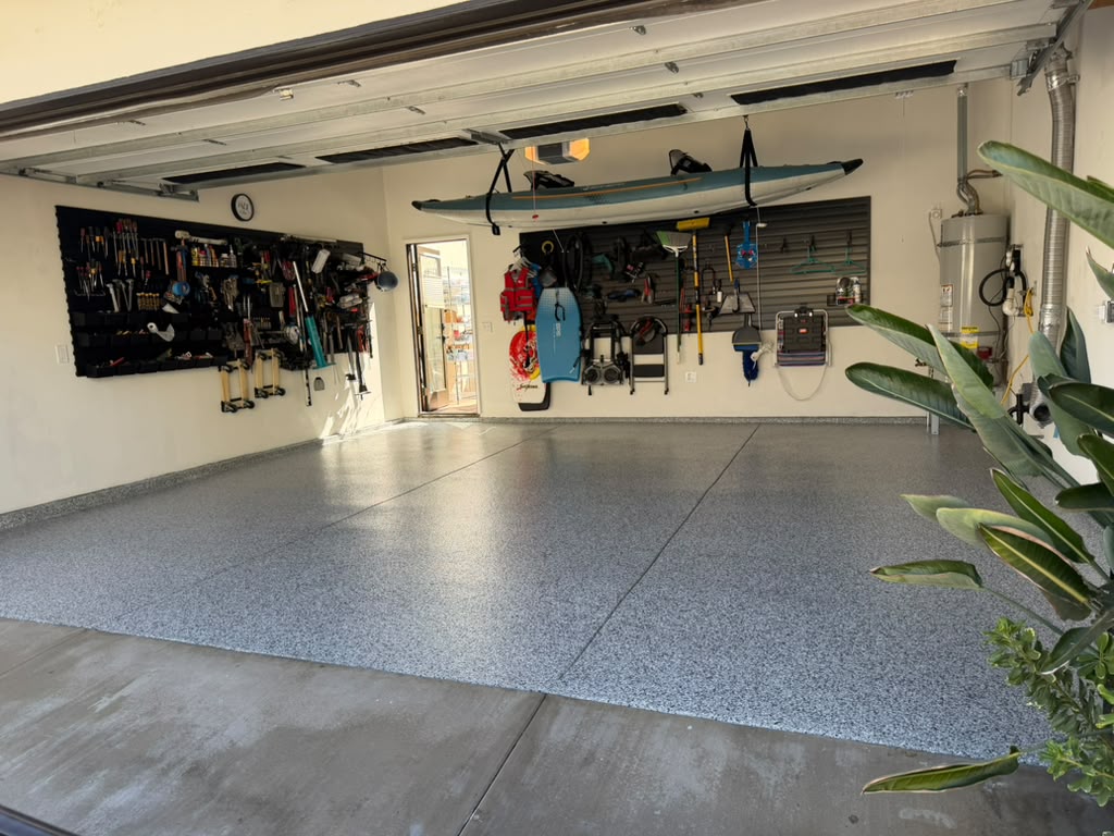 Gravel flake polyaspartic floor in a Long Beach two-car garage, with tools and a kayak stored on the walls