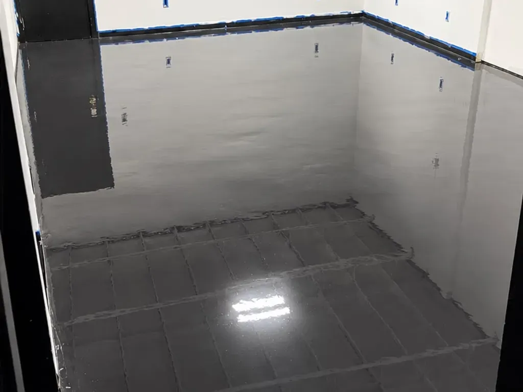 Finished high-gloss black polyaspartic floor in the Los Angeles warehouse storage room, reflecting the white walls