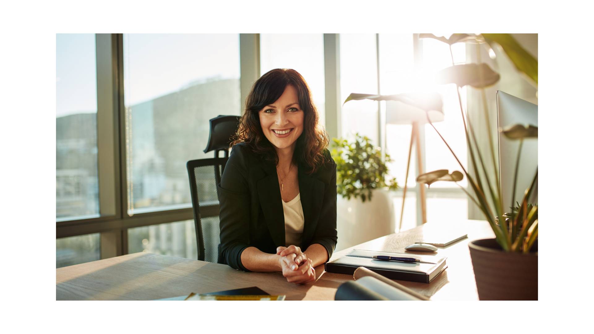 Lächelnde Geschäftsfrau im Büro, symbolisiert Professionalität und Positivität in einer modernen Arbeitsumgebung mit Tageslicht.