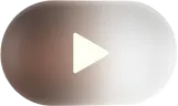 Oval play button icon with a white right-pointing triangle on a blurred gray background.