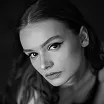 Close-up black and white portrait of a young woman with light makeup, looking at the camera.
