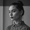 Black and white portrait of a woman with hair bun and long earrings looking slightly left.