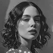 Black and white portrait of a woman with curly hair wearing a polka dot shirt.