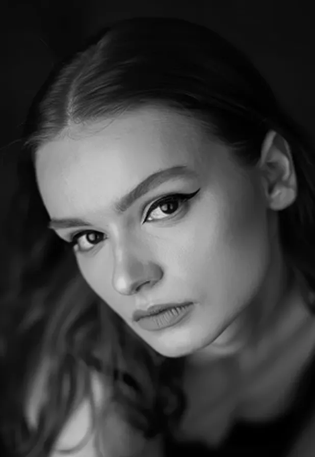 Close-up black and white portrait of a woman with winged eyeliner looking into the camera.