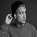 Young man in a beanie and sweatshirt looking to the side with a pensive expression.