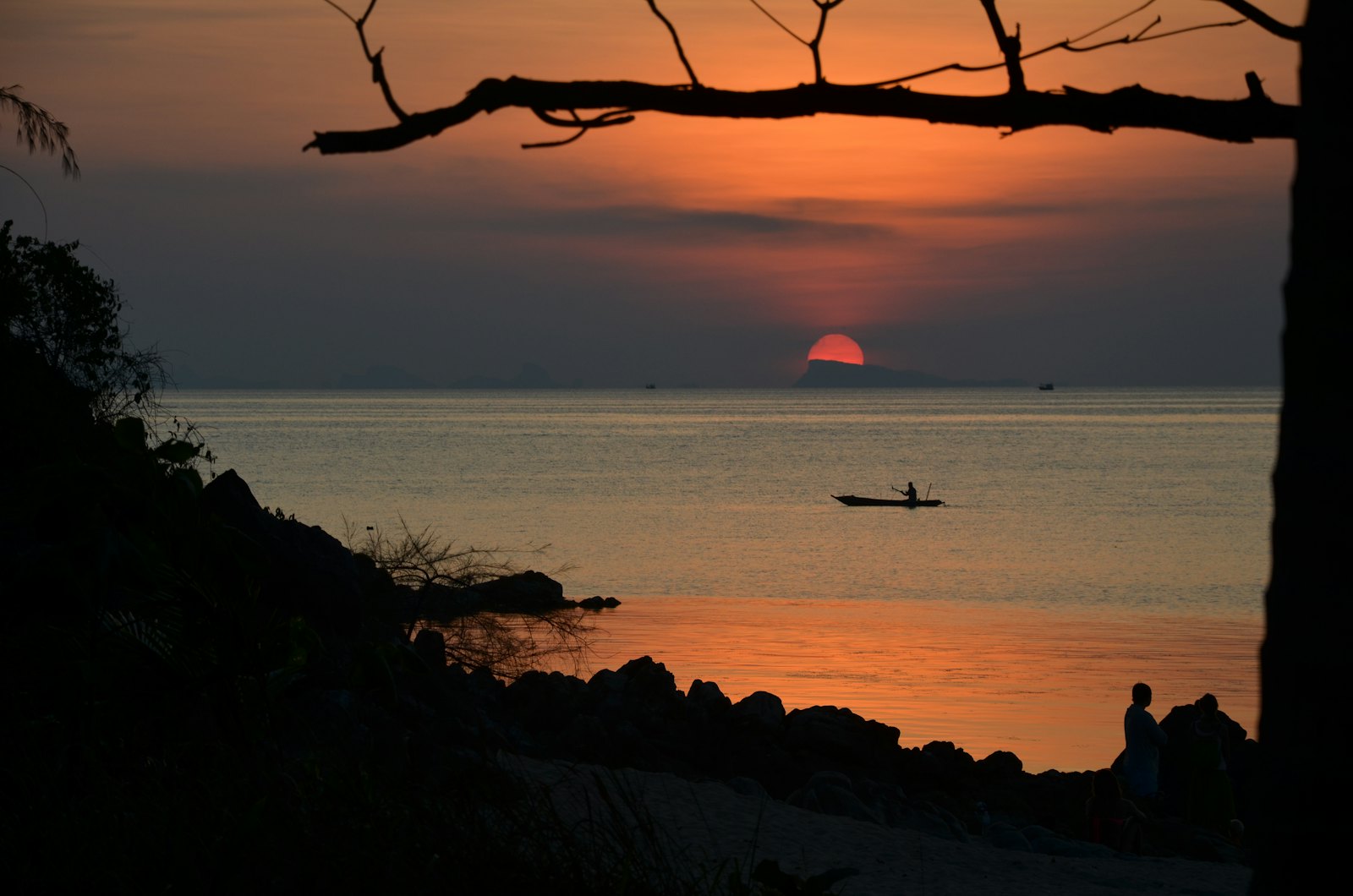 Sunset over the sea at Koh Phangan with a boat silhouette