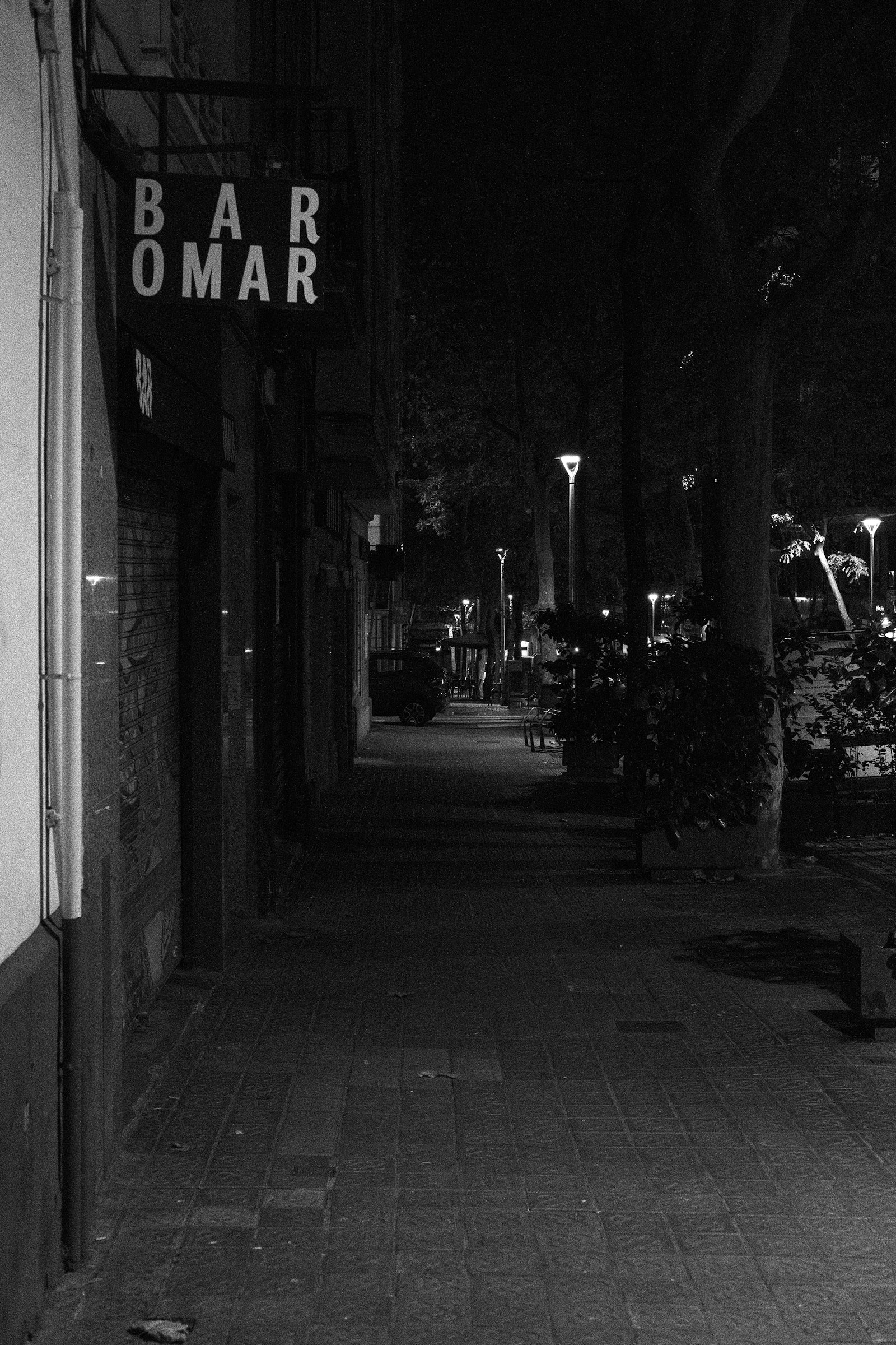 Barcelona street at night with a bar sign