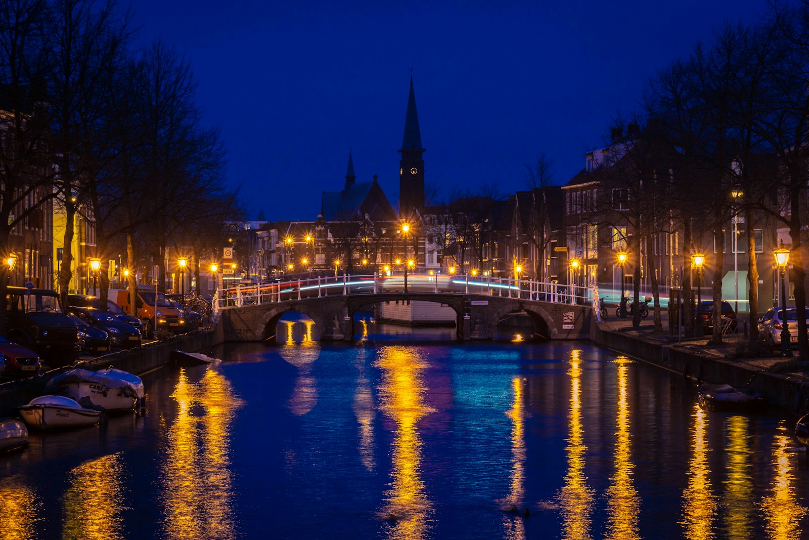 A bridge over a canal with street lights at night in Leiden, Netherlands. Photo by Petr Slovacek on Unsplash (Unsplash License)