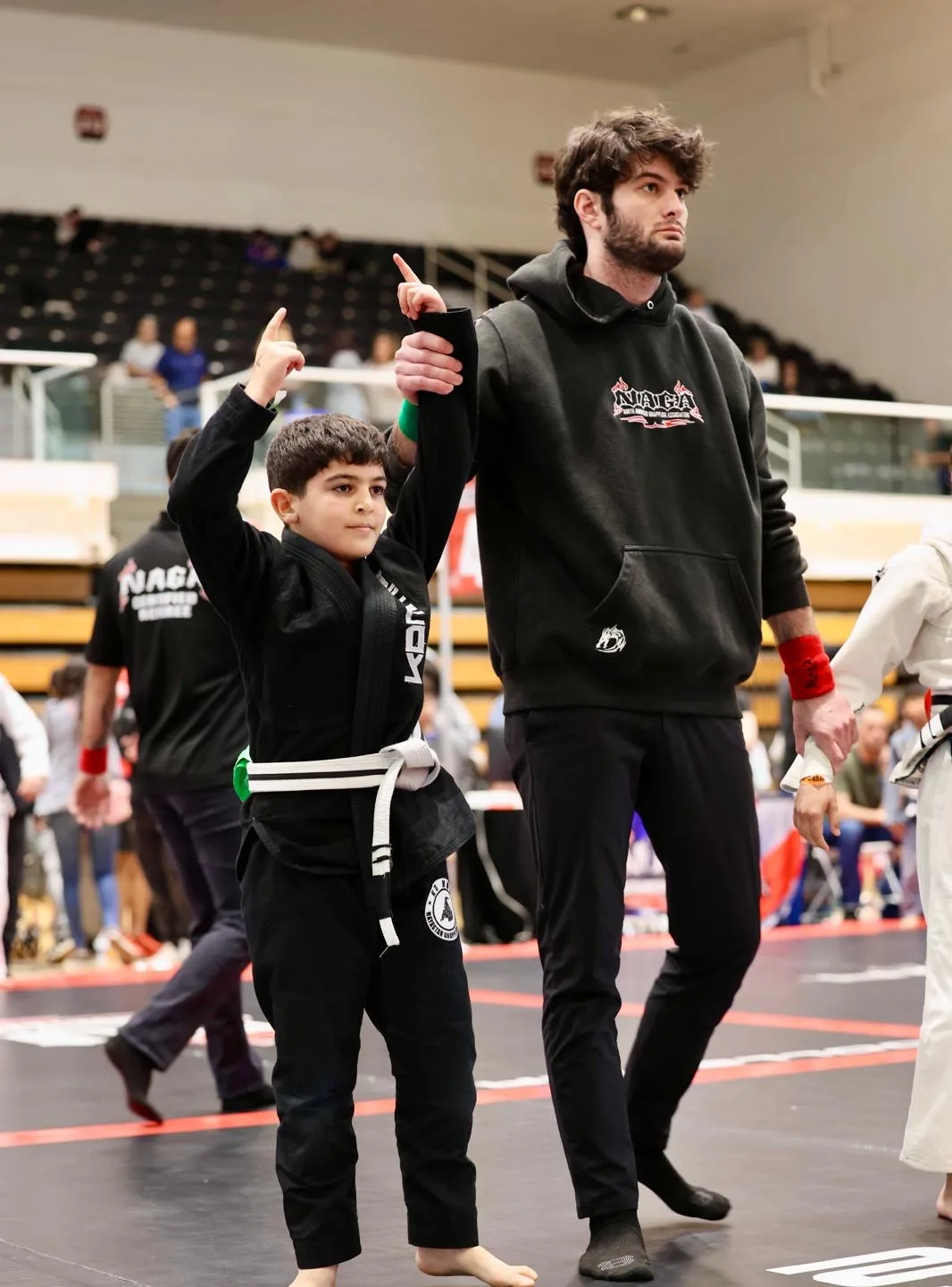 KD MMA coach raising a young competitor's arm after a win