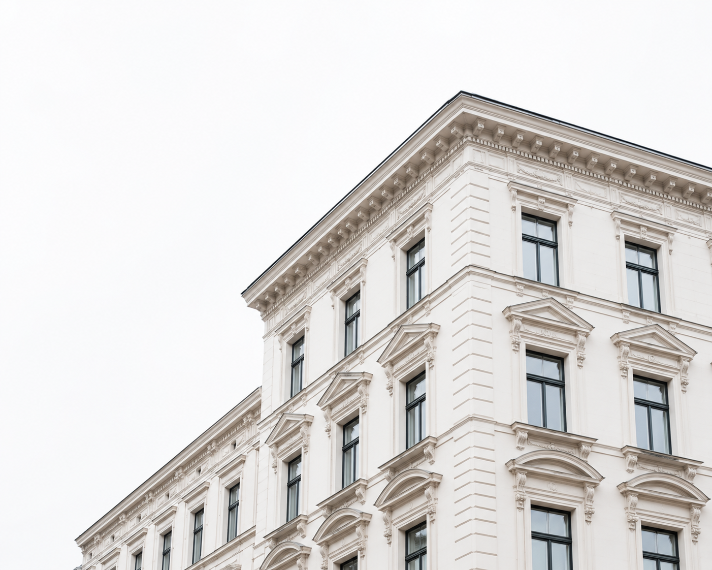 Elegantes weißes Gebäude mit vielen Fenstern und verzierten Fassaden im klassischen Stil.