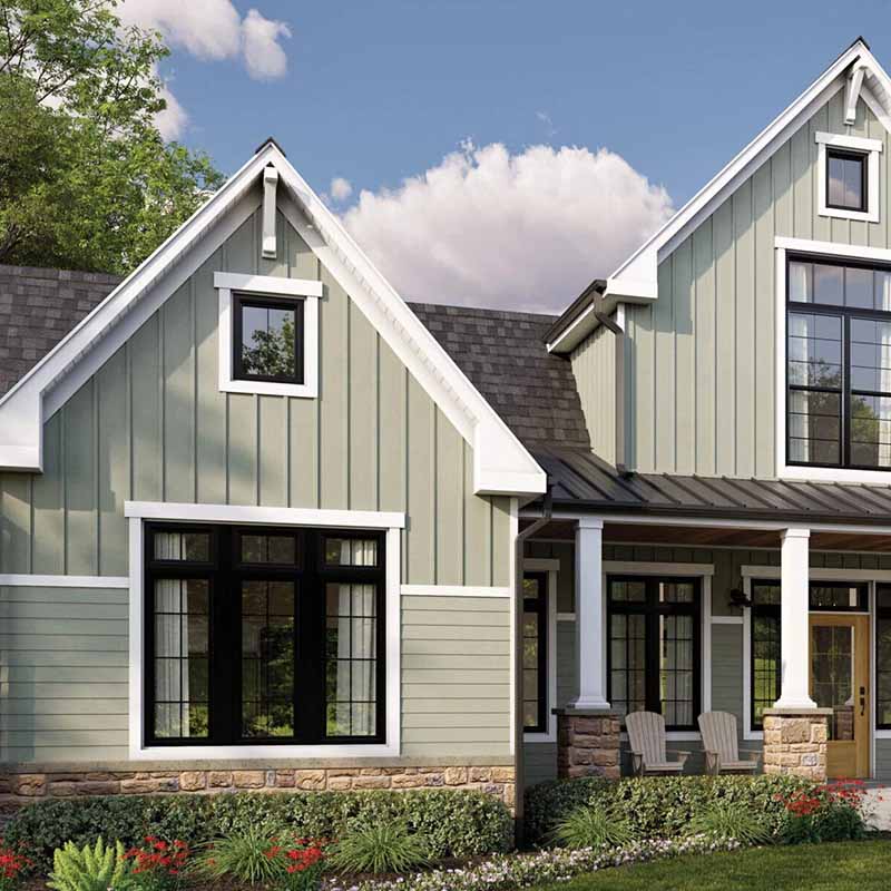 Two-story house with green siding and white trim on a clear day.