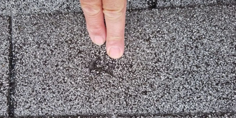 Fingers pointing at hail damage on a Cleveland, Ohio roof