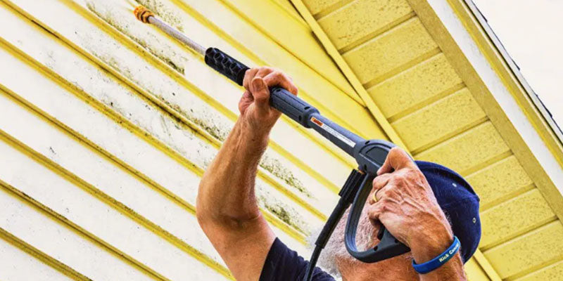 Man power-washing vinyl siding on a Mansfield, Ohio home