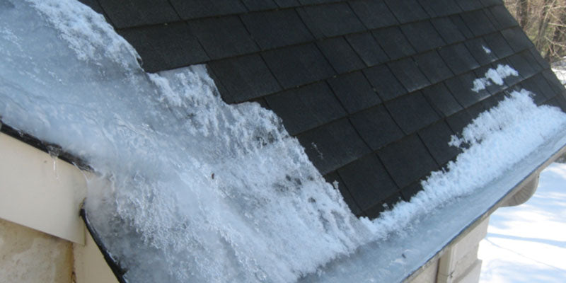 Snow accumulation on a roof edge with a dark shingled roof