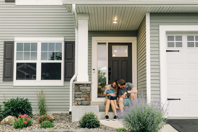 Family sitting on front porch of their home