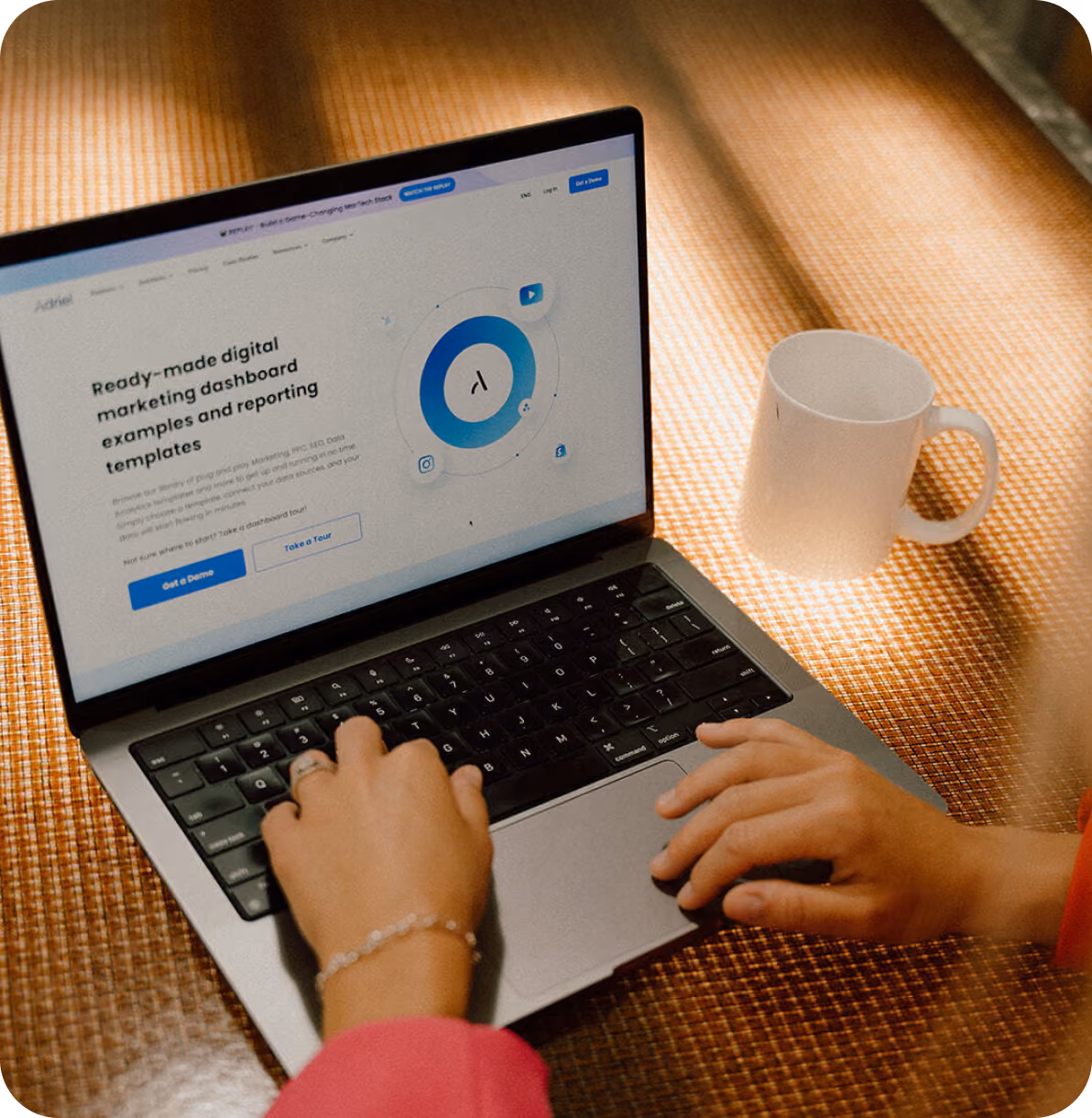 Hands typing on a laptop showing a digital marketing dashboard webpage with a white mug nearby.