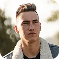 Portrait of a young man with styled hair wearing a shearling-collar jacket outdoors.