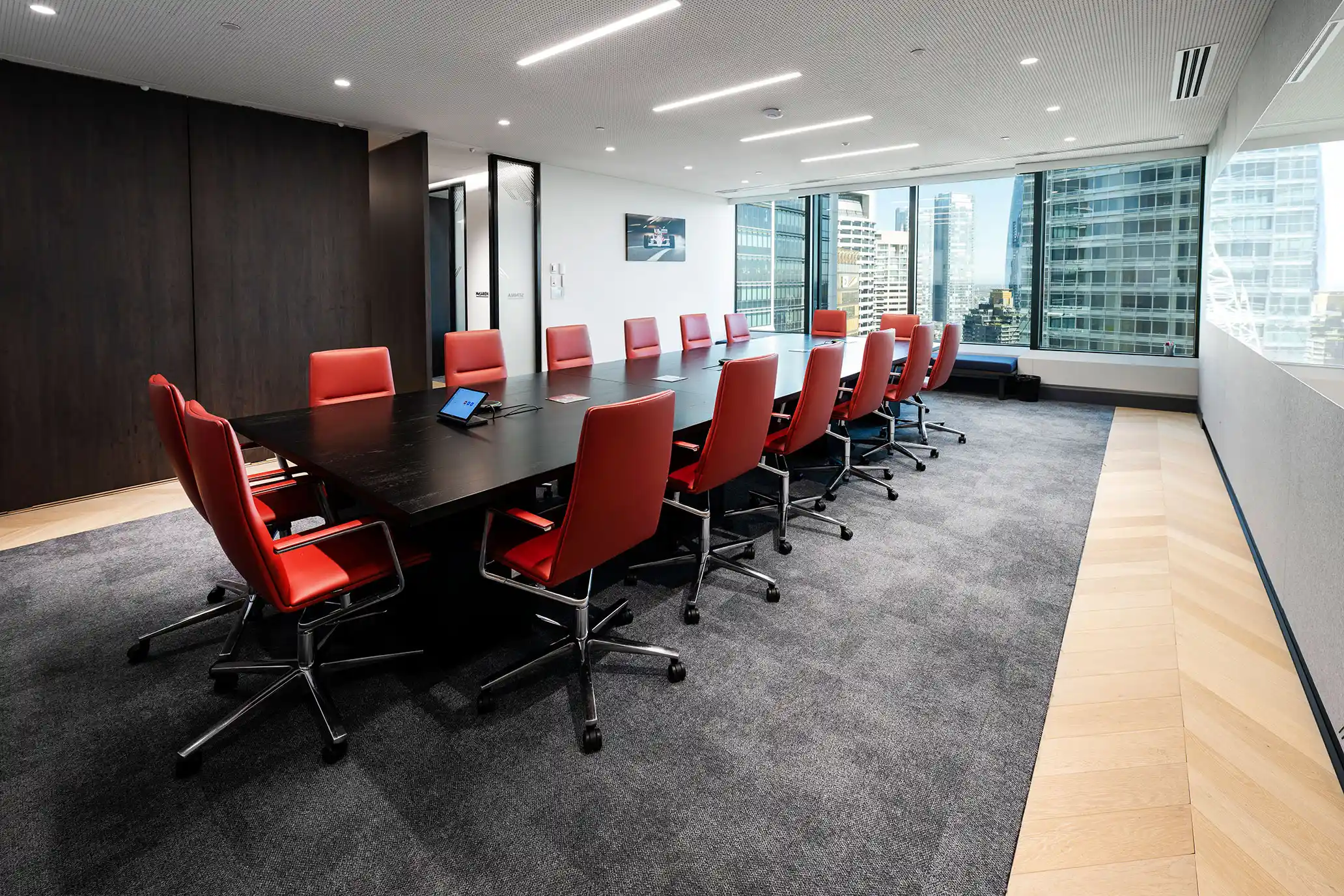 Modern office with rows of desks, computers, chairs, large windows, plants, and shelves with files.