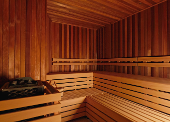 Interior of a wooden sauna with tiered benches and a heater with sauna stones.