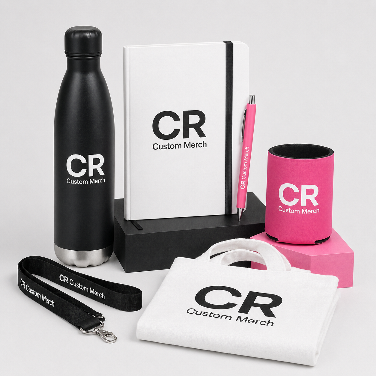 CR Custom Merch branded drink bottle, notebook, pen, lanyard, tote and stubby holder in a studio display