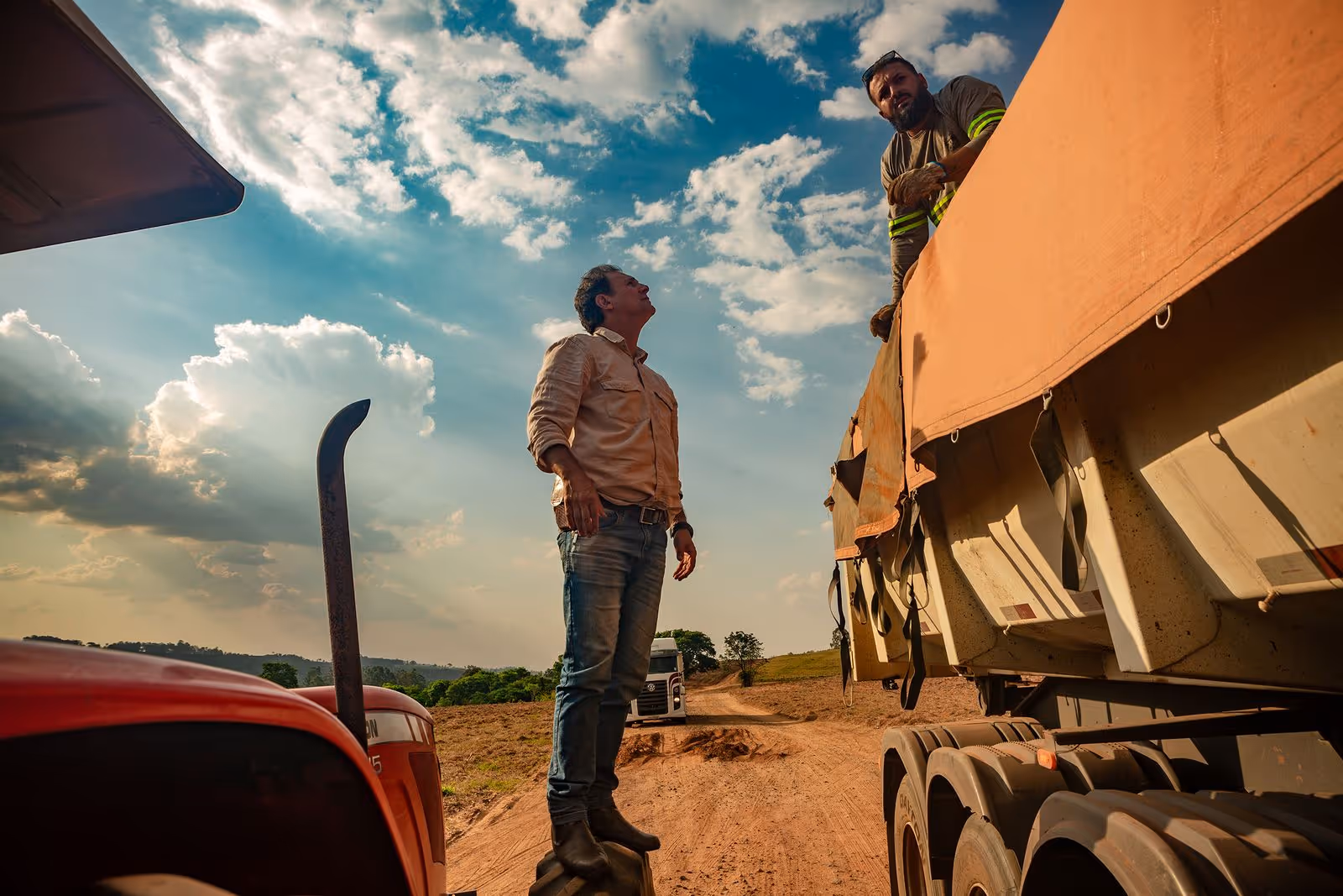 Man on rural road inspecting a truck loaded with rock powder