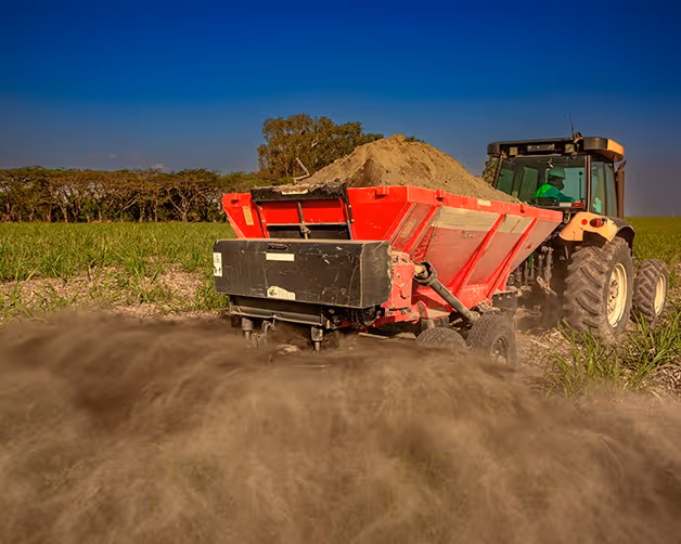 A tractor spreading rock powder over a field