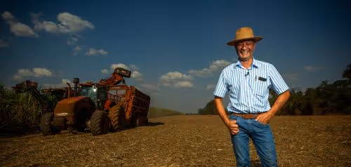 Farmer standing beside agricultural machinery on harvested farmland used for large-scale carbon removal and soil improvement projects.