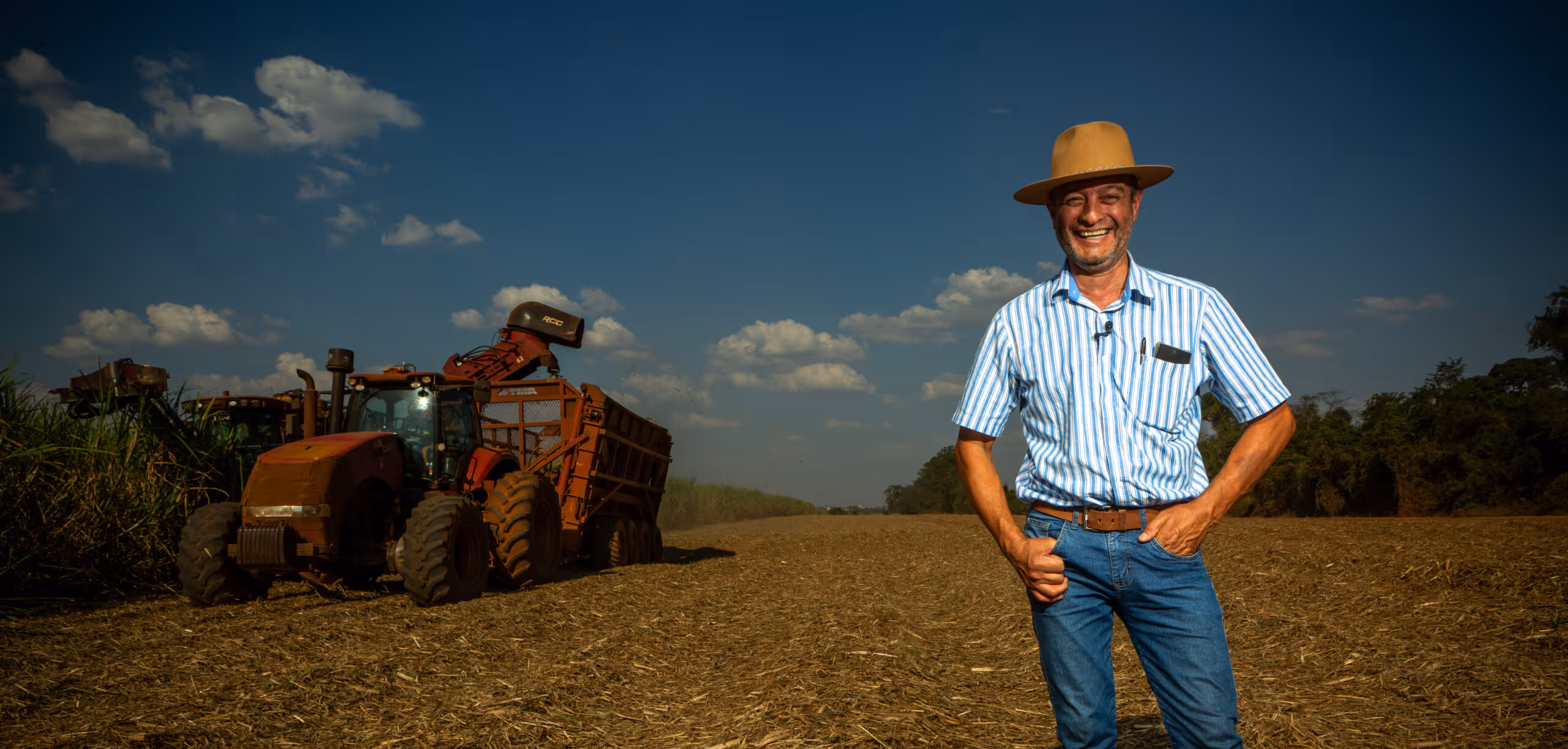 Farmer standing beside agricultural machinery on harvested farmland used for large-scale carbon removal and soil improvement projects.