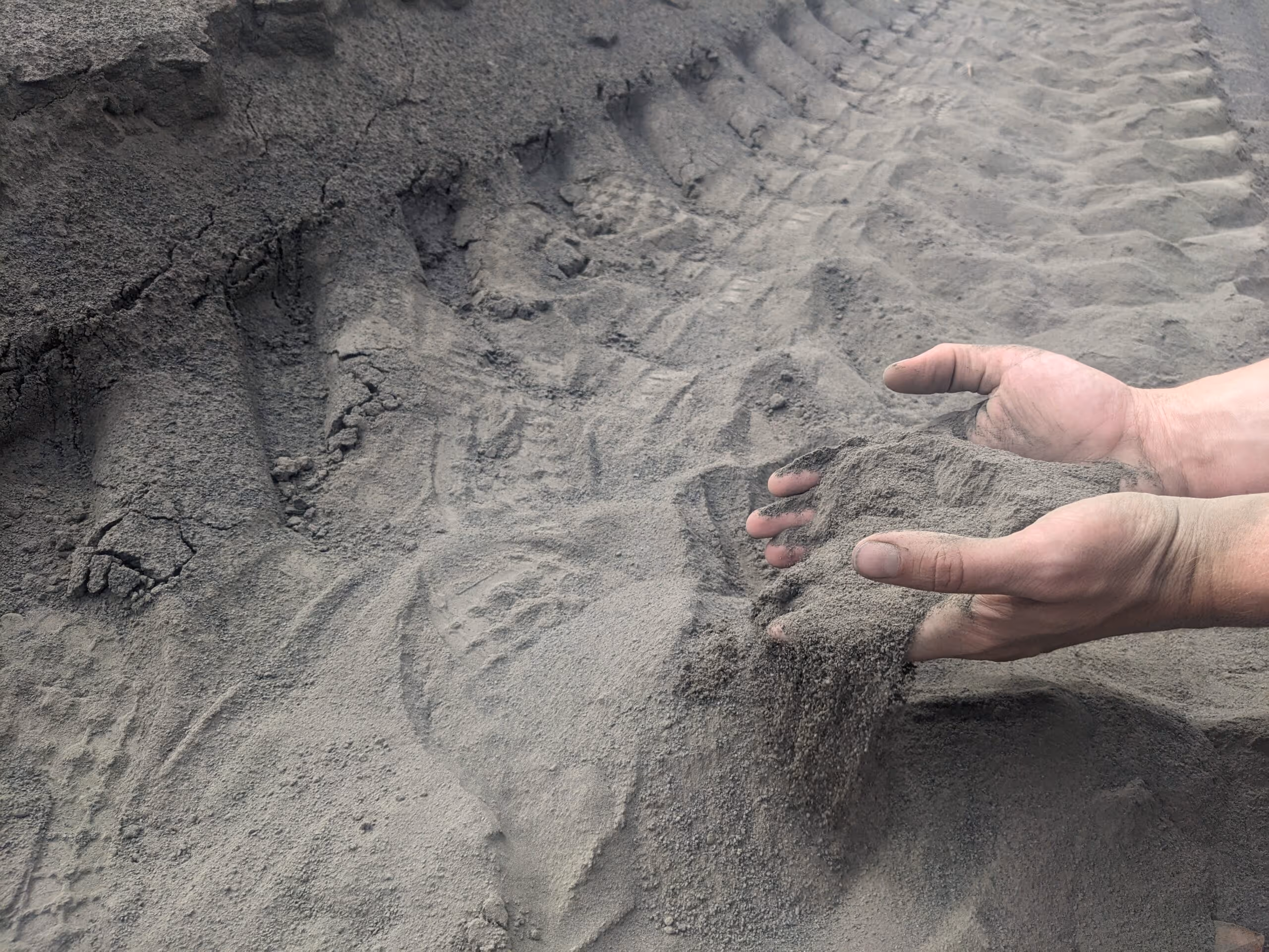 Hands holding finely ground silicate rock powder used in enhanced rock weathering for carbon dioxide removal.