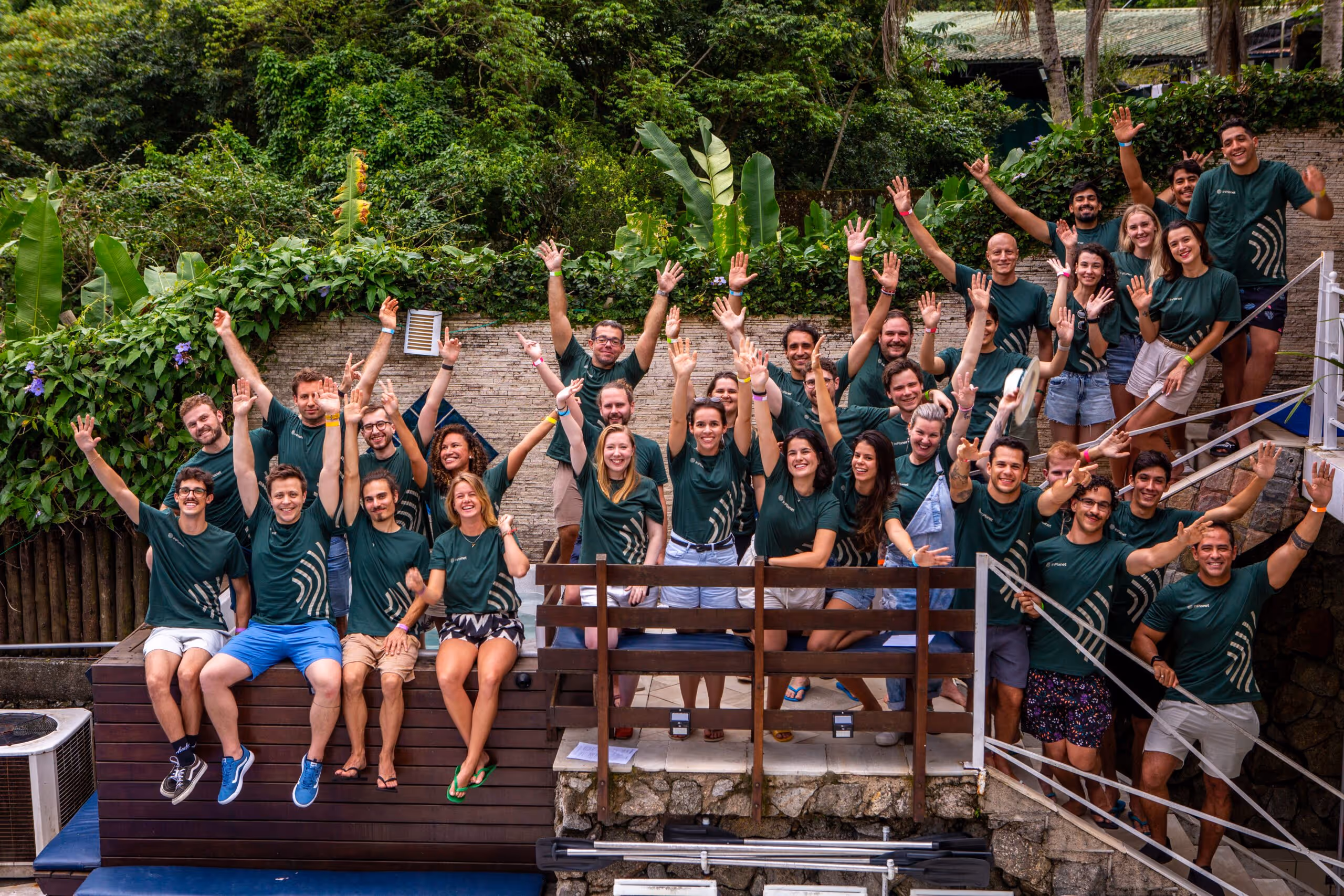 InPlanet team of 30 people on March 2024. The team is standing on a stairwell and have their hands up celebrating teh company achievements