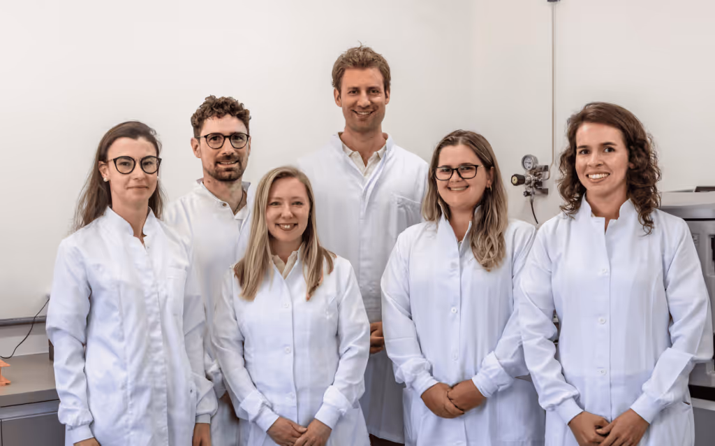 Science team standing in the lab wearing white lab coats.