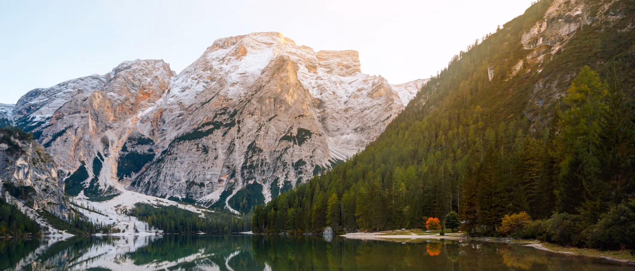 Mountain lake surrounded by forest and rocky peaks, highlighting the natural landscapes that help regulate Earth's climate.