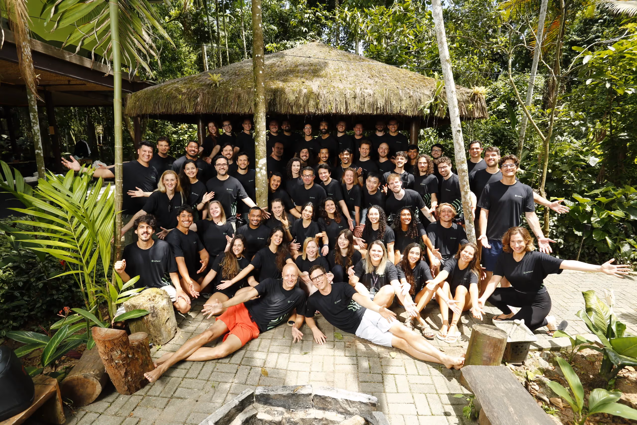 InPlanet team members gathered for a group photo at a rainforest retreat in Brazil, surrounded by tropical vegetation.