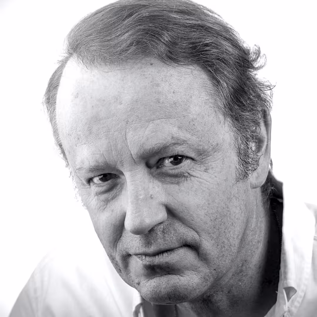 Black and white close-up portrait of a serious middle-aged man with receding hair and wrinkles.