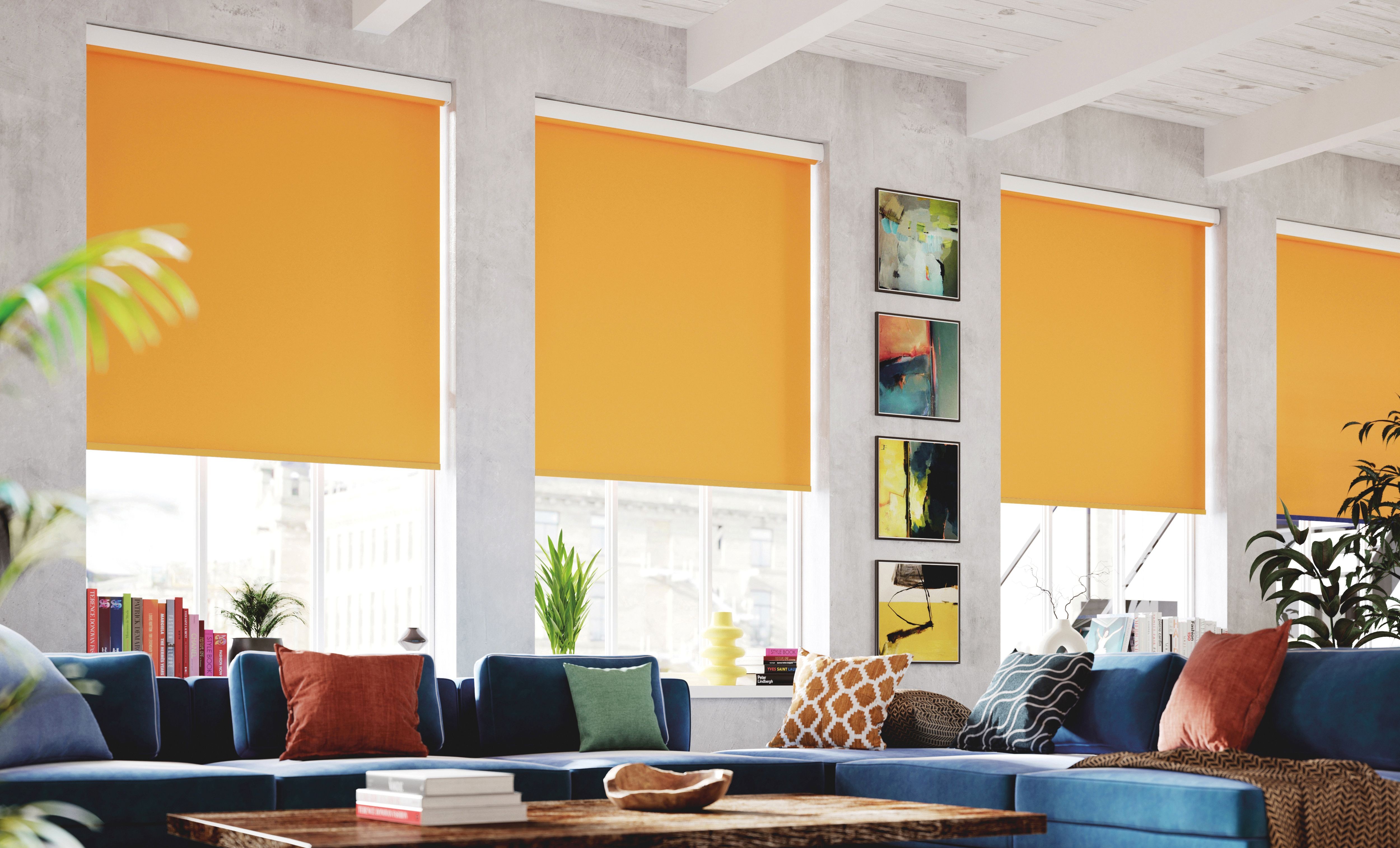 Modern living room with blue sectional sofa, colorful pillows, orange roller shades, and wall art.
